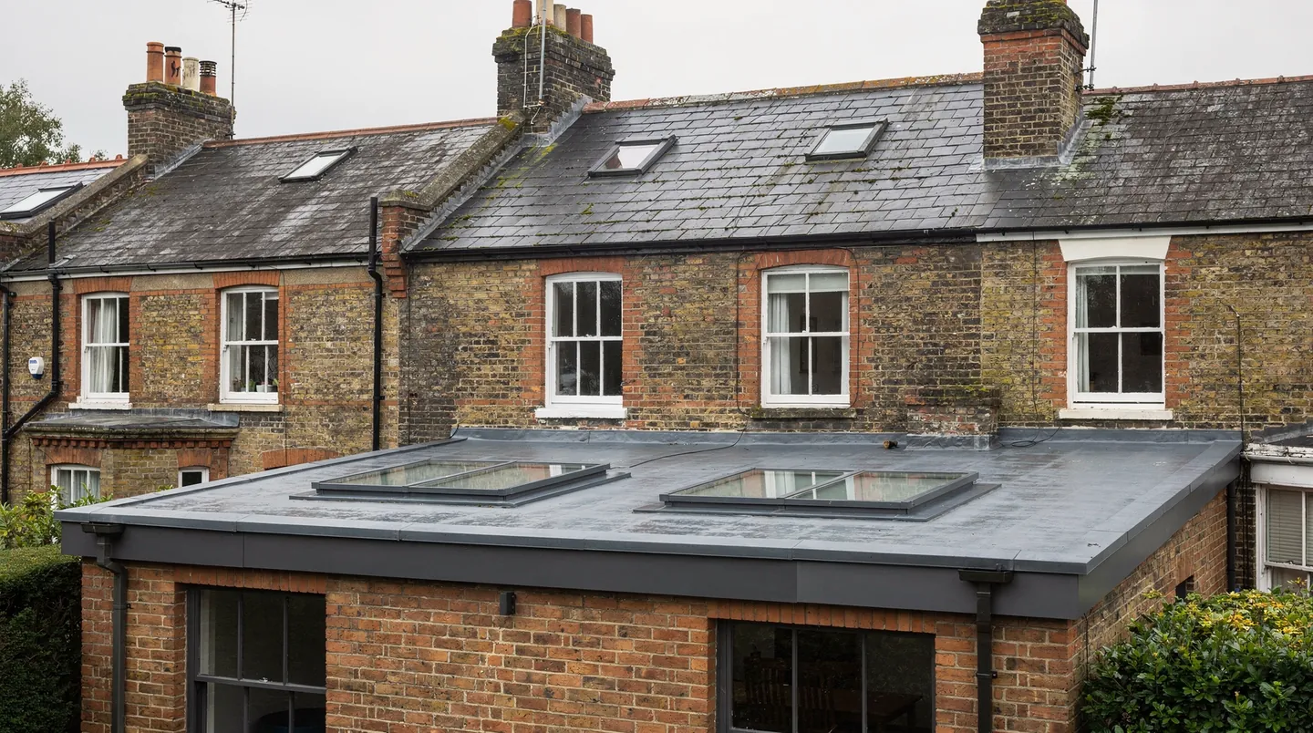A pair of low flat rooflights over a terrace extension, tucked behind the parapet