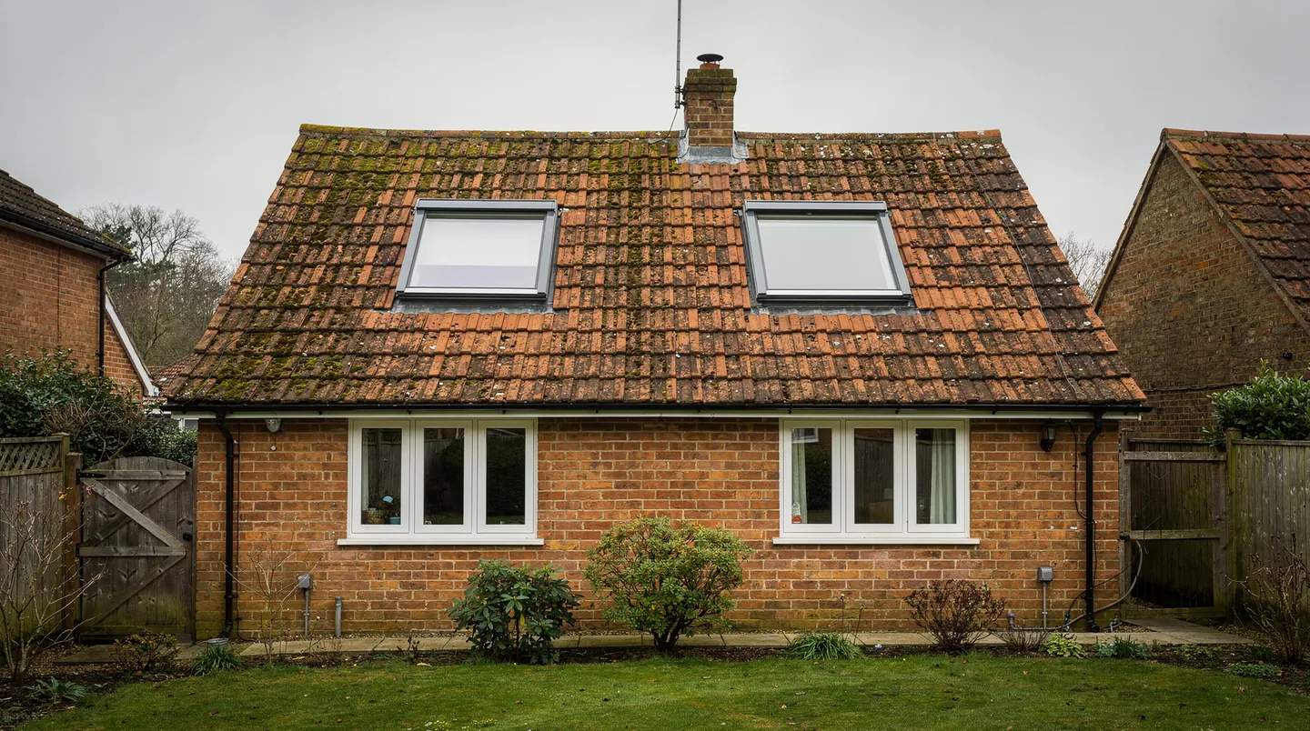 Two roof windows fitted low in a clay tile slope with flashing kits around each frame