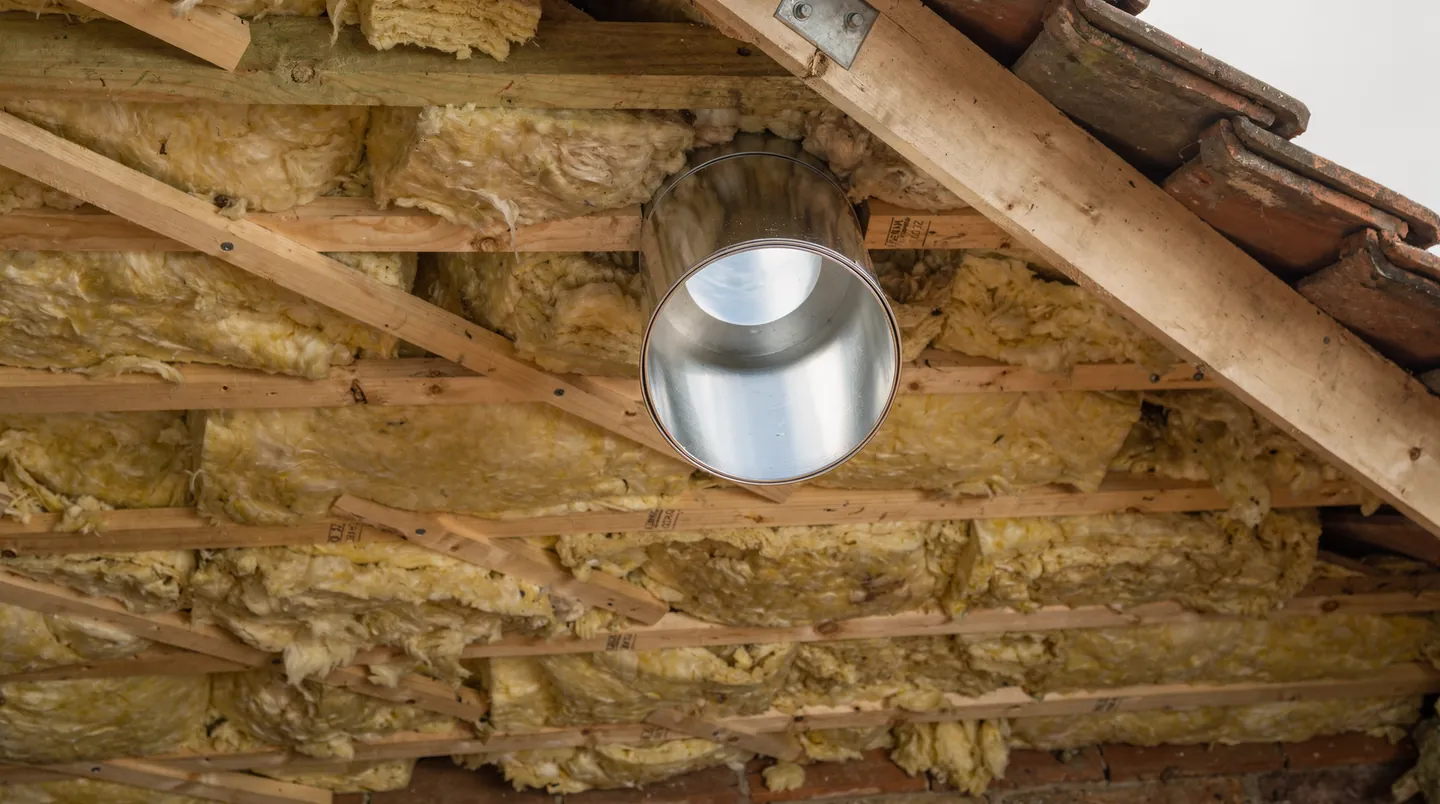 A reflective sun tunnel tube passing through loft insulation between the joists