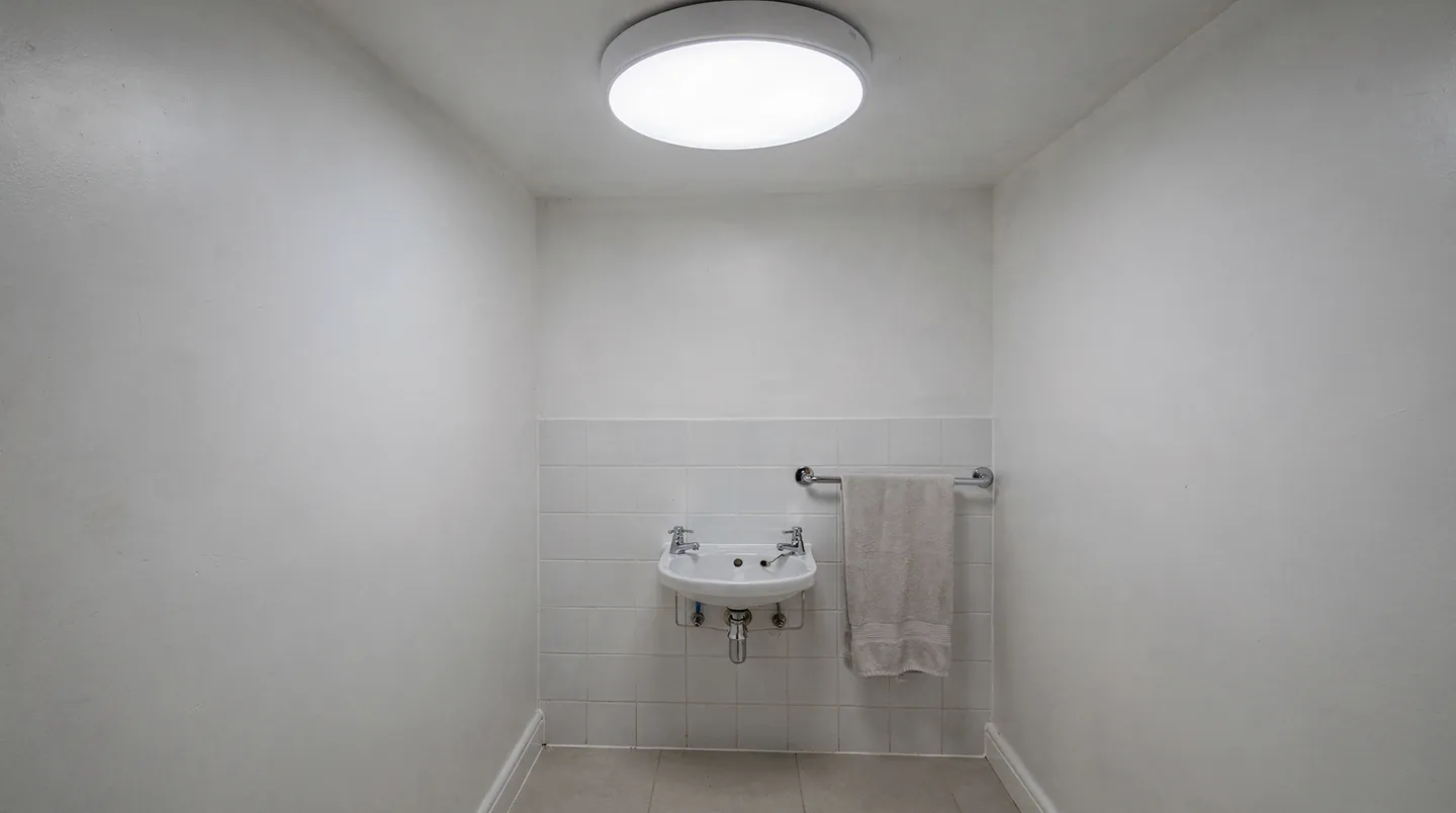 A windowless cloakroom lit by a round sun tunnel diffuser in the ceiling