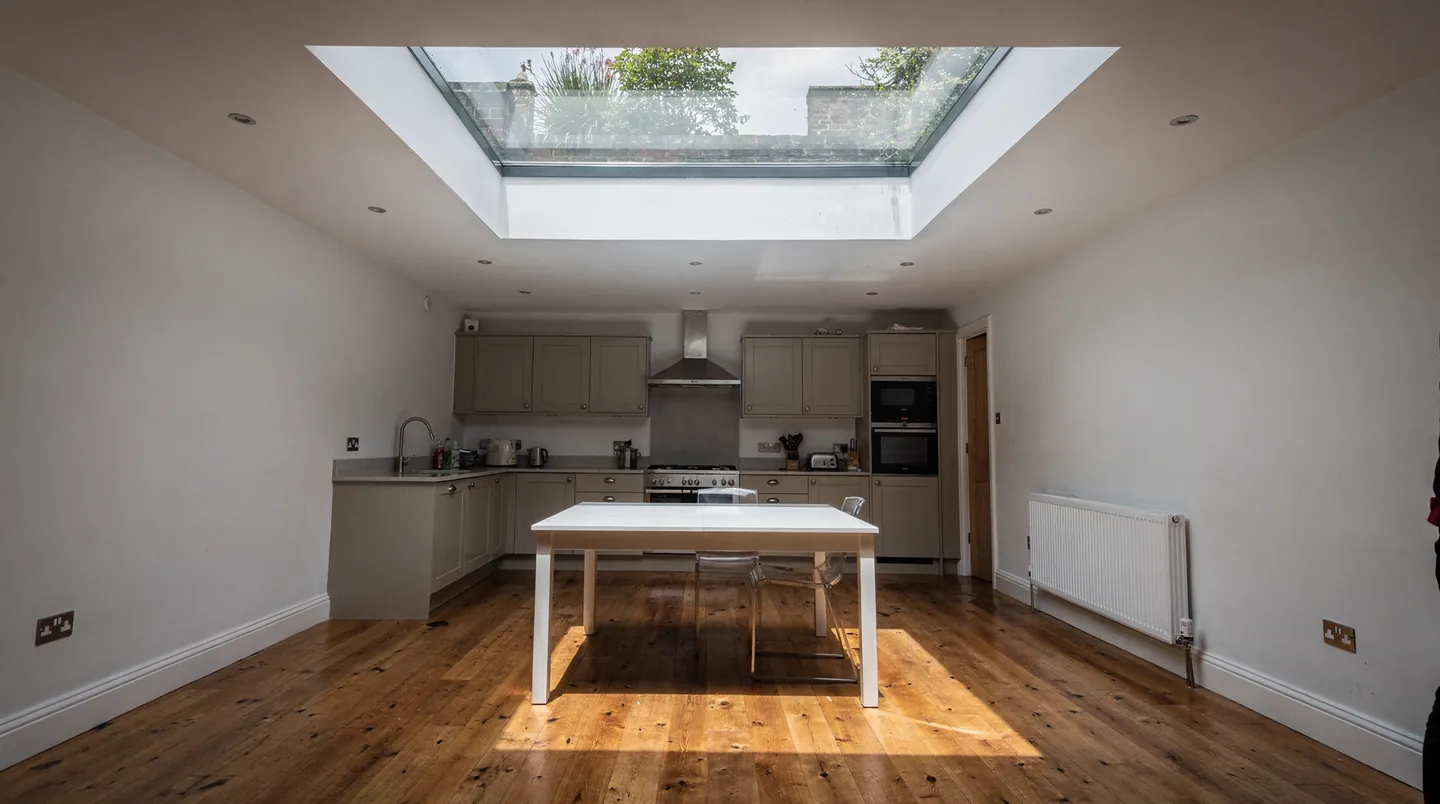 A kitchen lit through a large glass panel in the ceiling, with the garden above