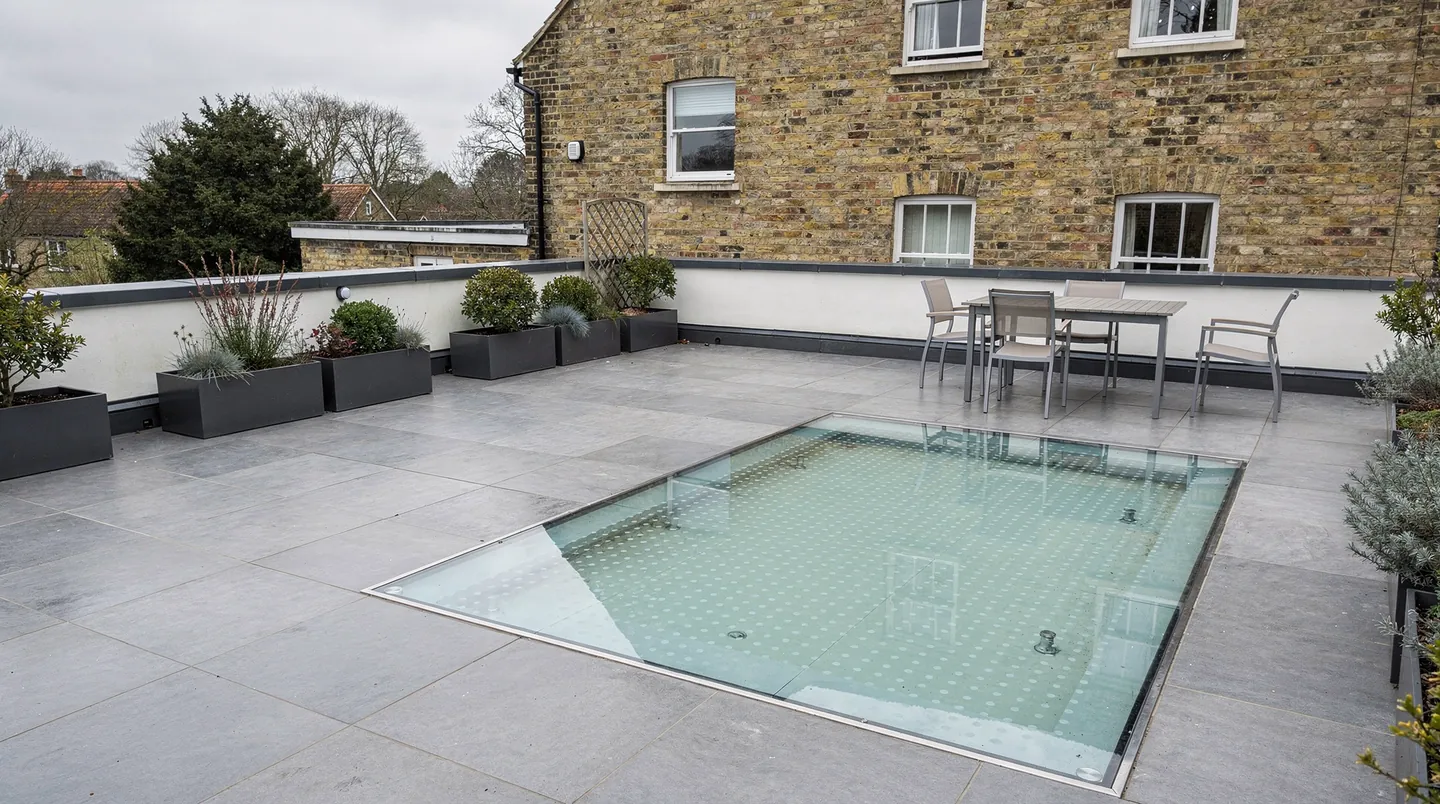 A walk-on glass panel set level with grey paving on a roof terrace
